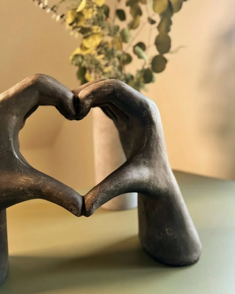 Betonskulptur aus zwei Händen die ein Herz formen als Symbol für Verbundenheit und innere Klarheit.